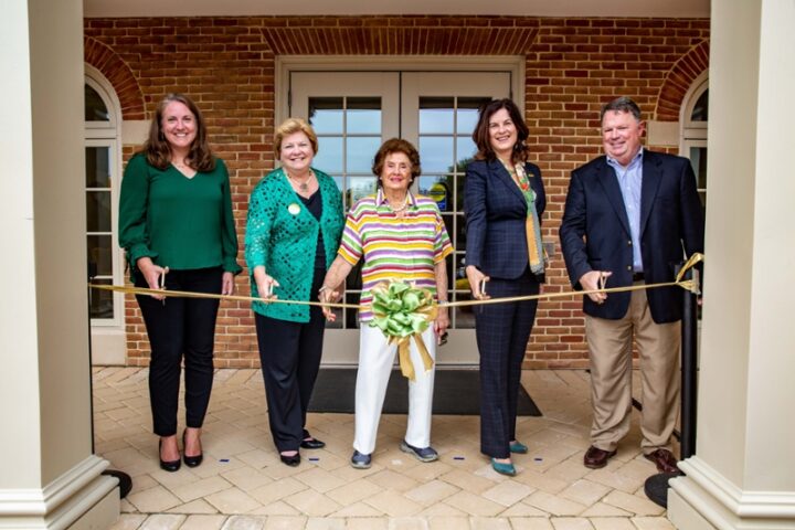 People hold scissors to cut a ribbon on a building