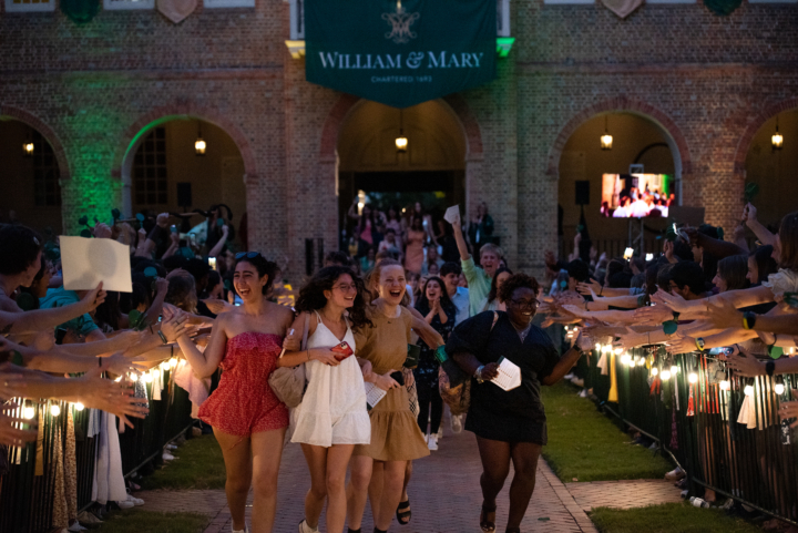 Students celebrating as they run down a line of oustretched hands