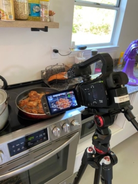 A camera is set up to film food cooking on a stove