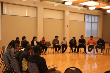 Men sitting in a circle in chairs eating plates of food