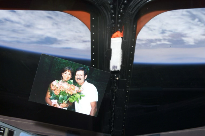 A photo of a couple in front of a window through which the Earth can be seen from space