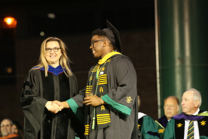 Man accepting award while shaking hands with woman