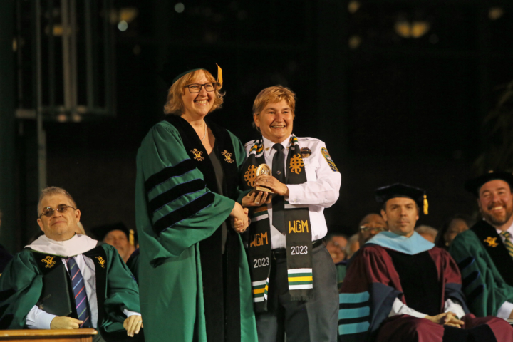 Two people pose for a photo together while holding an award.