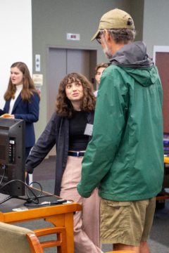 Two people talk to each other near a computer screen