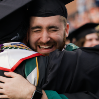 Two people in caps and gowns embrace.