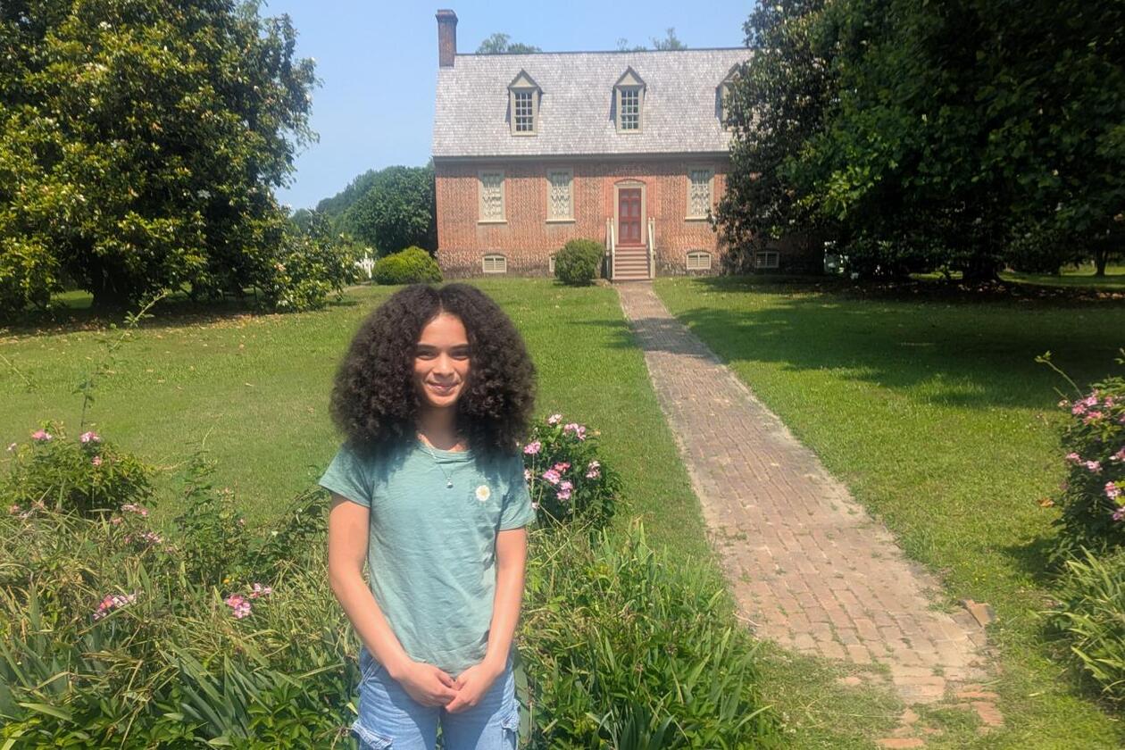 This is a photograph of Cadence Hodge, a Sharpe Community Scholar, who is A Woody intern this summer with Preservation Virginia. She is posing at the Smith's Fort site in Surry, Virginia.
