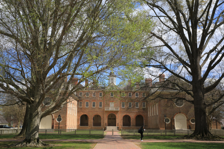A person walks in front of a large colonial-era brick building.