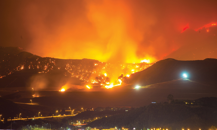 Fire illuminates hills at night.