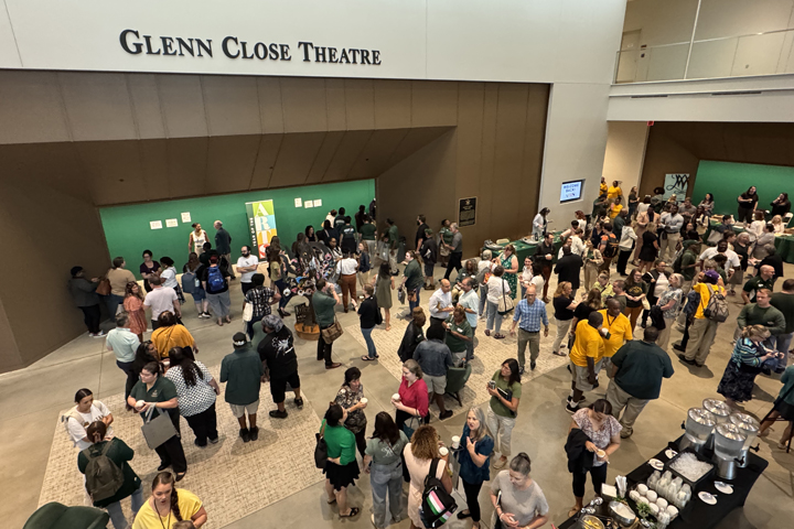 Dozens of people are seen talking and drinking coffee in a theater lobby.