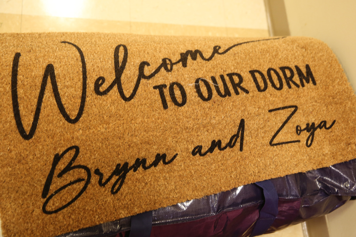 A welcome mat says "Weclome to our dorm, Brynn and Zoya."