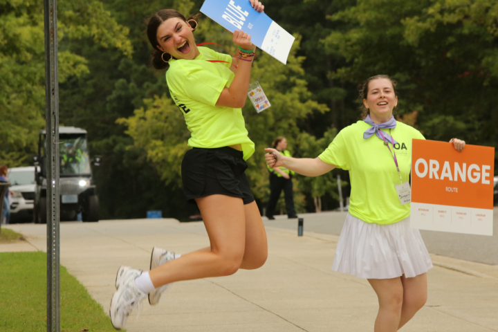 A person holding a sign leaps into the air while another holds a sign nearby.