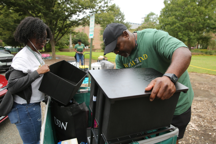 Two people stack a draw and other items on a pile in an outdoor location.