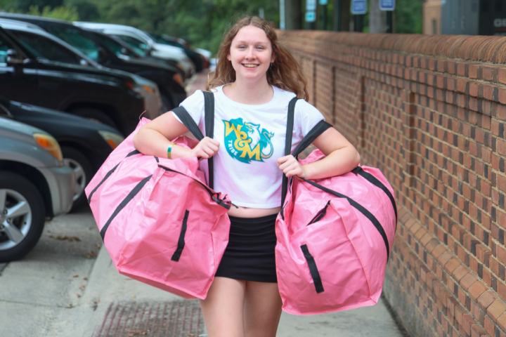 A person wearing a W&M short carries two pink bags.