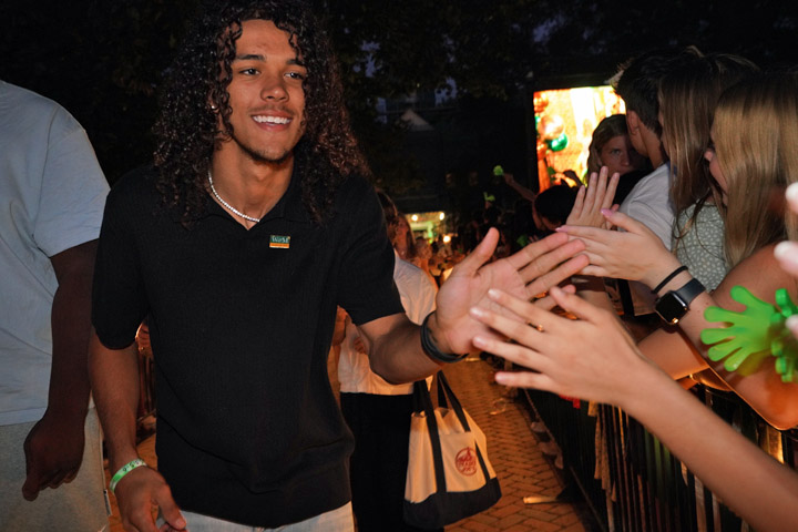 A person walks down a pathway, giving high-fives to people.