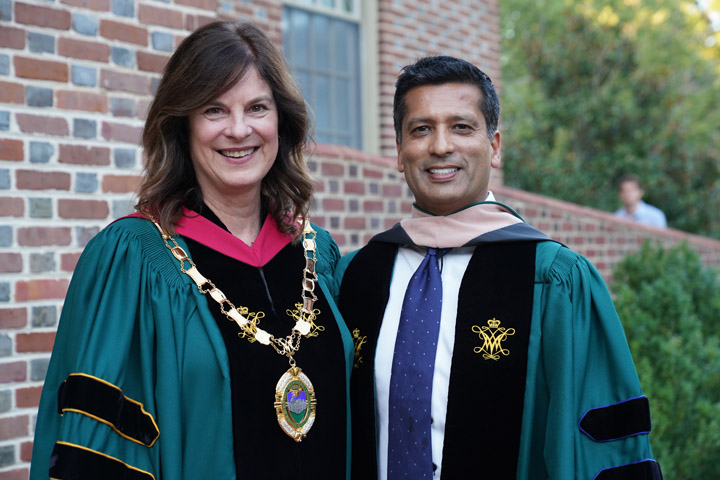Two people smile for a photo together while wearing academic regalia