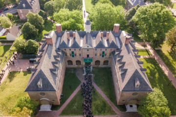 In an aerial photos, graduates wearing caps and gowns can be seen streaming into a large, brick building.
