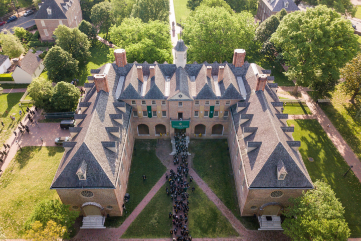 In an aerial photos, graduates wearing caps and gowns can be seen streaming into a large, brick building.