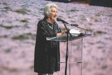 Jane Batten speaks into a microphone while standing at a podium.