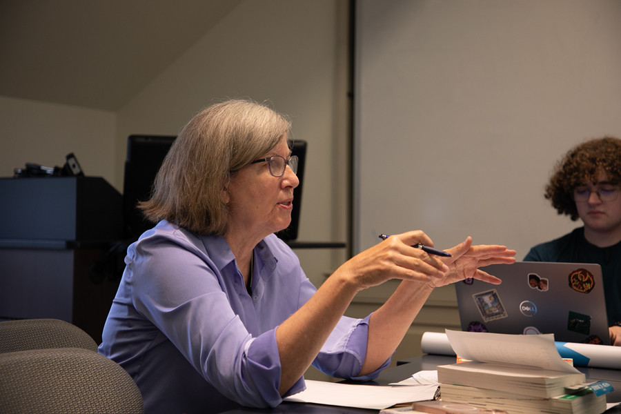 Hilary Holladay gestures with a pen in her hand while sitting at a table.