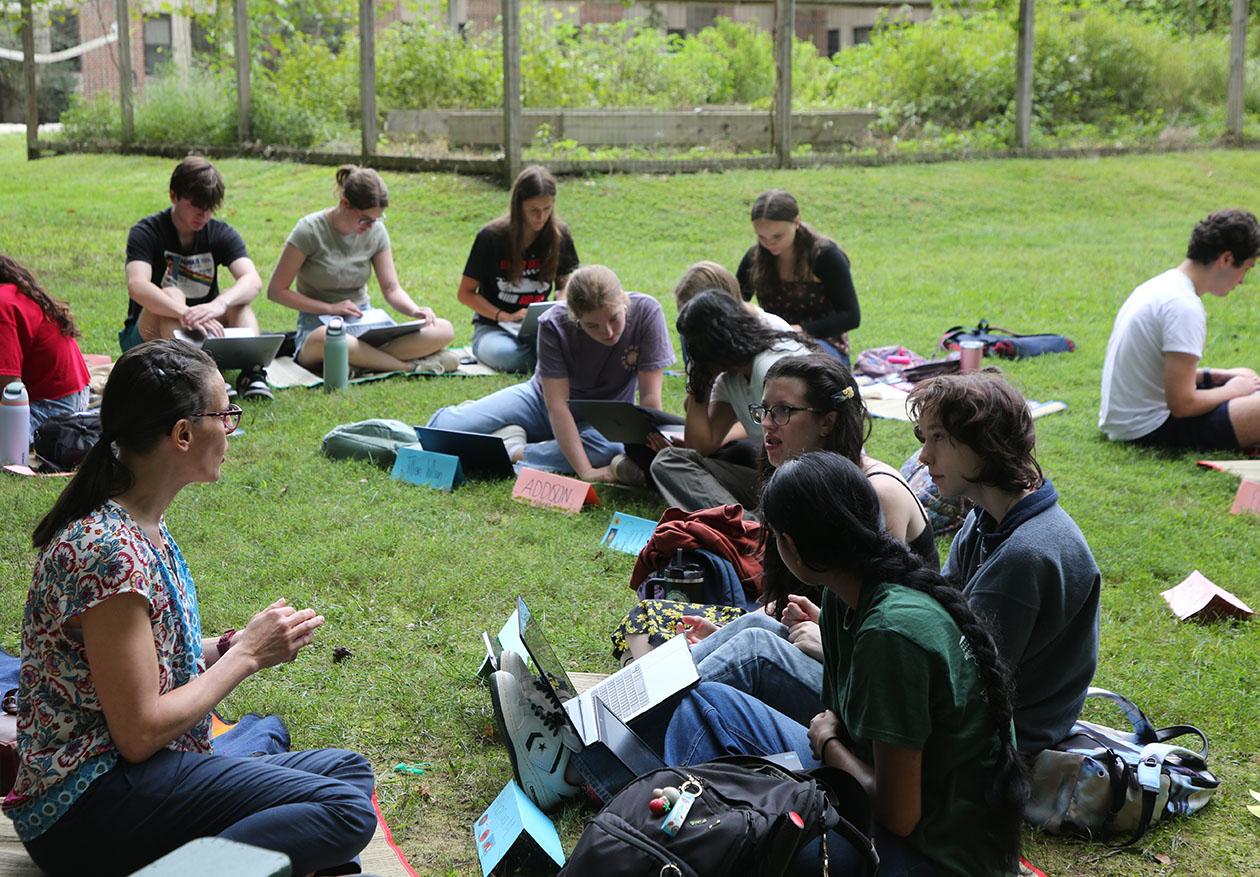 Photo of professor and students sitting on grass.