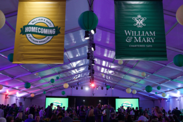 William & Mary and Homecoming banners hang from a ceoling of a large tent, in which people dance.
