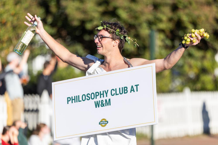 A person dressed in a toga wear a sign that says philosophy club at W&M