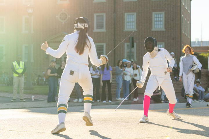 People fence while standing on a street.