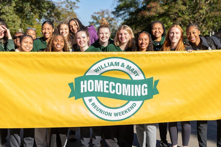 People pose with a large sign that says Homecoming.