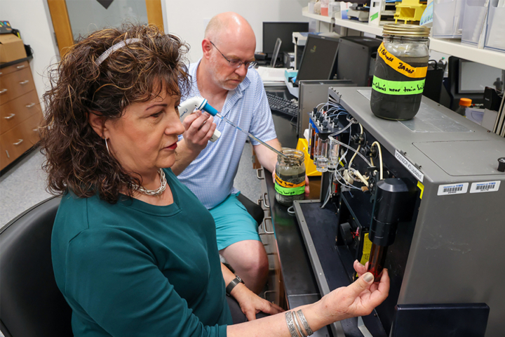 People in a lab look at lab equipment.