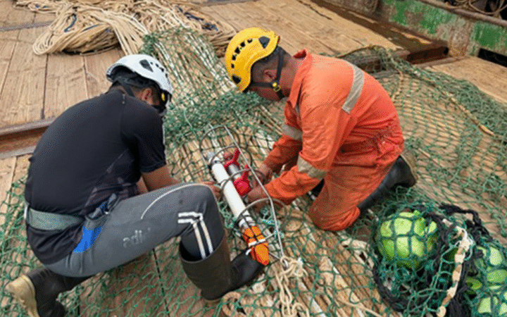 People wearing helmets and boots work on a device in nets.
