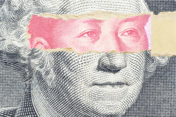 A graphic shows a piece of a dollar bill torn open at over the the eyes of George Washington, revealing other eyes underneath.
