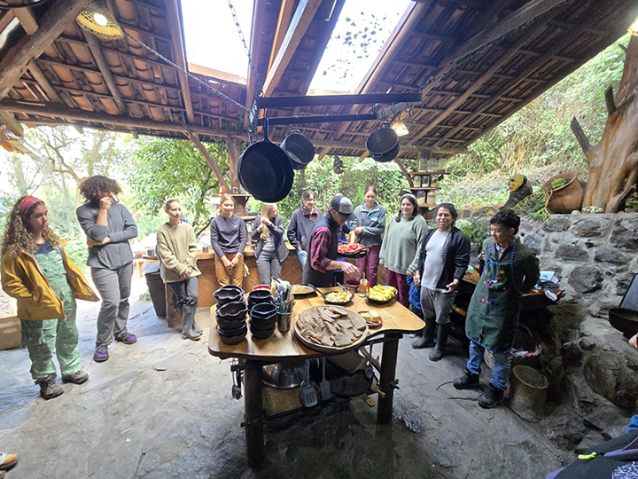 People gather around a table in an outdoor kitchen.