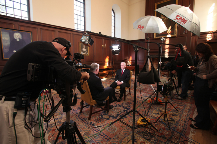 People sit in a large room surrounded by camera equipment.