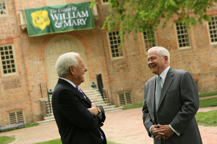 Two people laugh while standing outside of a large building with a William & Mary on it.
