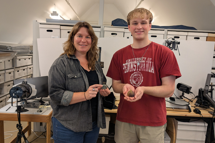 Two people smile for a photo together while holding 3D-printed objects.