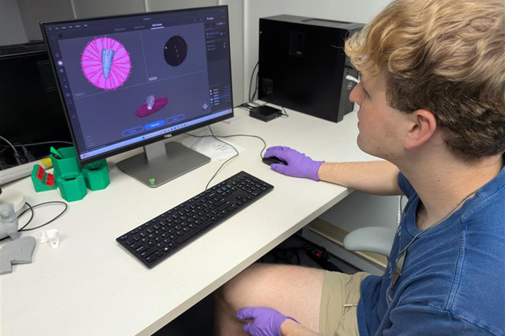 A person works on a computer while wearing purple gloves.