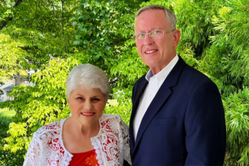 Two people pose for a photo in an outdoor location.