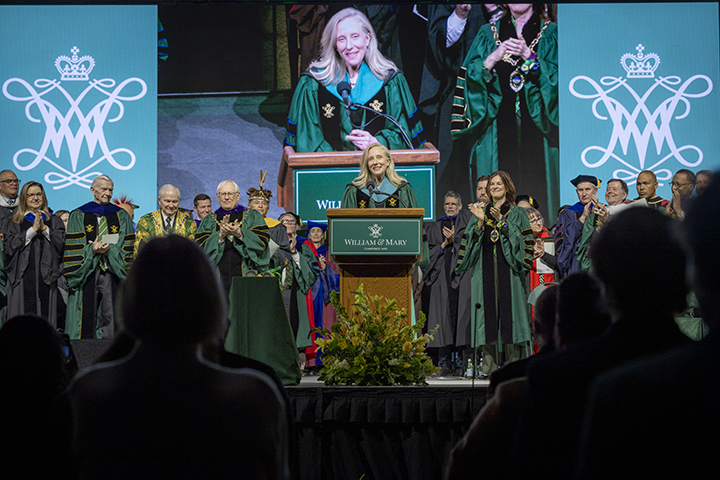 Abigail Spanberger stands at a podium while people surrounding her stand and applaud.