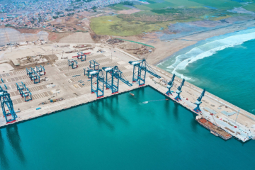 An aerial view of a port shows a docks and several cranes to be used for offloading and loading ships.