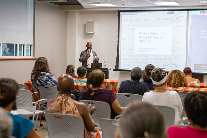 Jajuan Johnson speaks into a microphone at the front of a classroom.