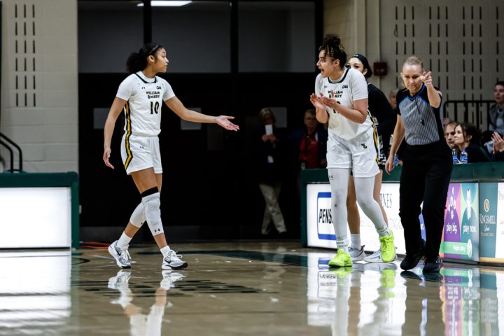 A basketball player applauds while another holds out her hand during a game.