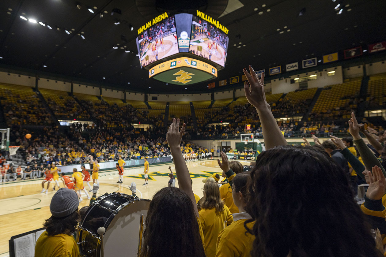 People a large arena cheer on basketball teams.