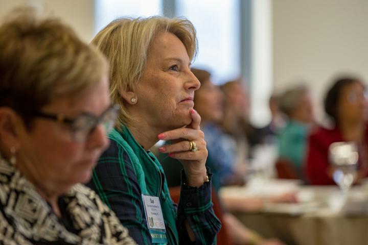 Sue Gerdelman listens to a speaker while leaning on her hand.