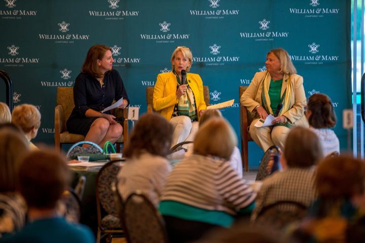 Sue Gerdelman and two others sit in the front of a room for a panel discussion.