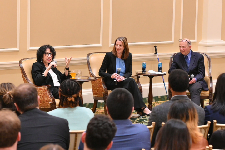 A person speaks into a microphone at the front of a room.