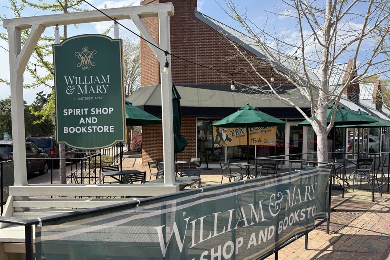 A sign for a spirit store and bookshop hangs in front of a brick building with an outdoor patio.