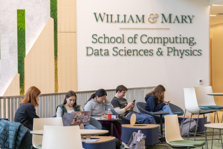 PEople sit at tables in a lobby near a sign for the William & Mary School of Computing, Data Sciences & Physics