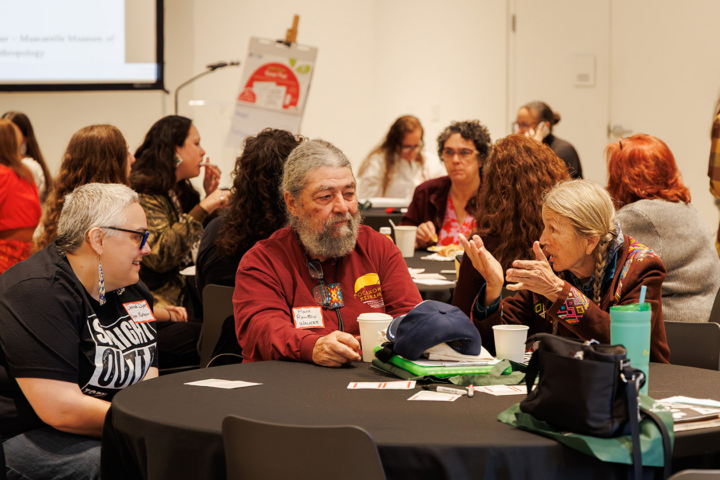 People sit around circular tables and engage in discussions.