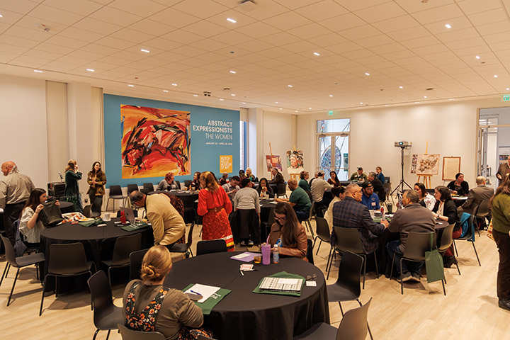 People gather at tables in a room at a museum.