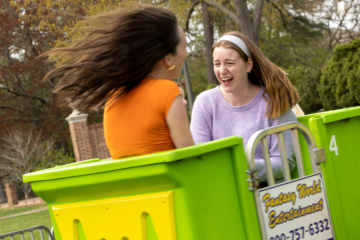 Two people ride a carnival-type ride.